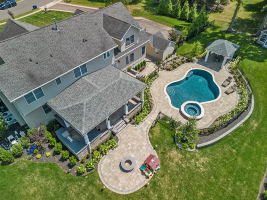 Behold the craftsmanship of Scenic View Landscaping with this expertly designed poolscape featuring a custom swimming pool, paver patio, and detailed garden elements.