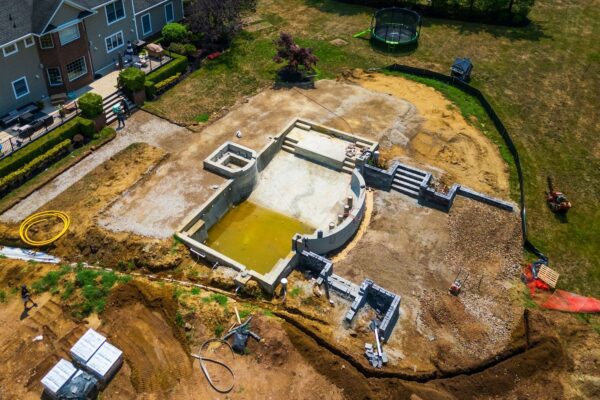 Complete outdoor living makeover in Colts Neck, NJ featuring a custom pool, raised patio, landscape lighting, sod lawn, outdoor kitchen, fire feature, and fully integrated landscape and hardscape design by Scenic View Landscaping.