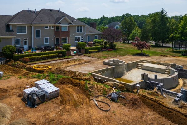 Complete outdoor living makeover in Colts Neck, NJ featuring a custom pool, raised patio, landscape lighting, sod lawn, outdoor kitchen, fire feature, and fully integrated landscape and hardscape design by Scenic View Landscaping.