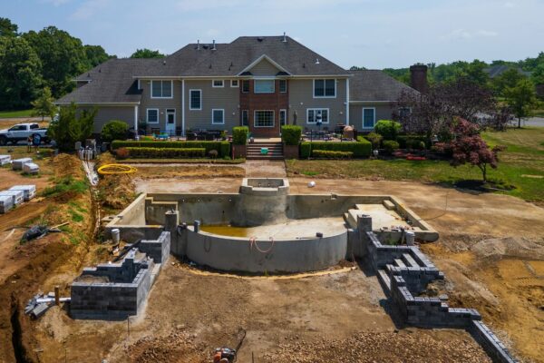 Complete outdoor living makeover in Colts Neck, NJ featuring a custom pool, raised patio, landscape lighting, sod lawn, outdoor kitchen, fire feature, and fully integrated landscape and hardscape design by Scenic View Landscaping.