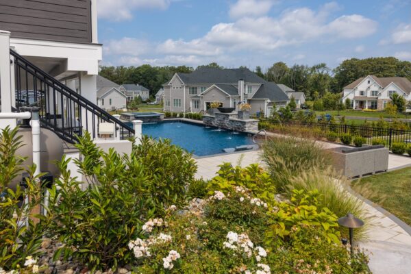 Scenic View Landscaping transformed a Lincroft, NJ property with a natural stone stairway, Techo-Bloc pool hardscaping, covered outdoor living area, and lush new landscaping.