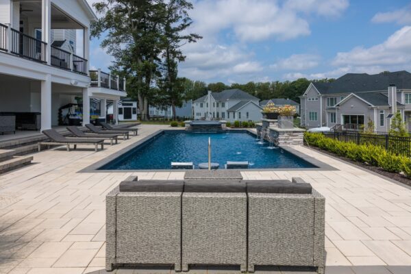 Scenic View Landscaping transformed a Lincroft, NJ property with a natural stone stairway, Techo-Bloc pool hardscaping, covered outdoor living area, and lush new landscaping.