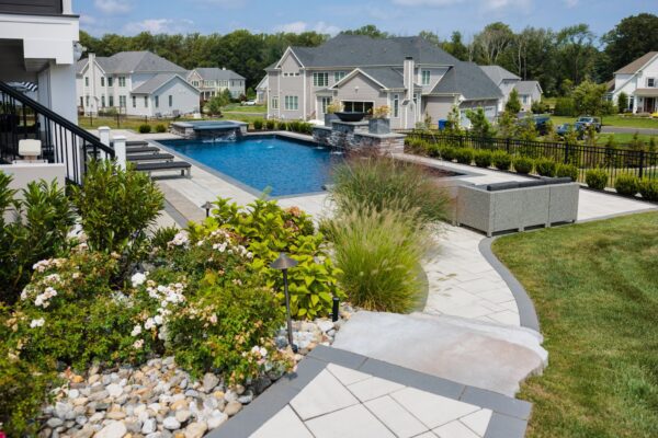 Scenic View Landscaping transformed a Lincroft, NJ property with a natural stone stairway, Techo-Bloc pool hardscaping, covered outdoor living area, and lush new landscaping.