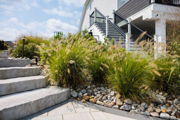 Scenic View Landscaping transformed a Lincroft, NJ property with a natural stone stairway, Techo-Bloc pool hardscaping, covered outdoor living area, and lush new landscaping.