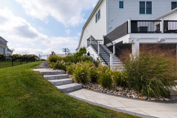 Scenic View Landscaping transformed a Lincroft, NJ property with a natural stone stairway, Techo-Bloc pool hardscaping, covered outdoor living area, and lush new landscaping.