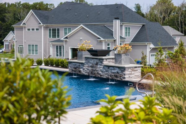 Scenic View Landscaping transformed a Lincroft, NJ property with a natural stone stairway, Techo-Bloc pool hardscaping, covered outdoor living area, and lush new landscaping.