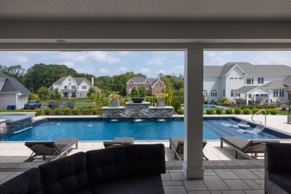 Scenic View Landscaping transformed a Lincroft, NJ property with a natural stone stairway, Techo-Bloc pool hardscaping, covered outdoor living area, and lush new landscaping.