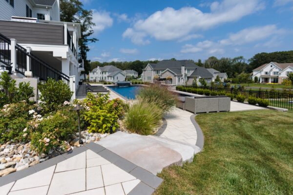 Scenic View Landscaping transformed a Lincroft, NJ property with a natural stone stairway, Techo-Bloc pool hardscaping, covered outdoor living area, and lush new landscaping.
