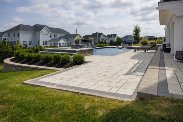 Scenic View Landscaping transformed a Lincroft, NJ property with a natural stone stairway, Techo-Bloc pool hardscaping, covered outdoor living area, and lush new landscaping.