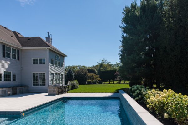Scenic View Landscaping transformed a Colts Neck backyard into a modern outdoor oasis with Techo-Bloc pavers, Raffinato coping, triple waterfall spillways, outdoor kitchen, and custom lighting.