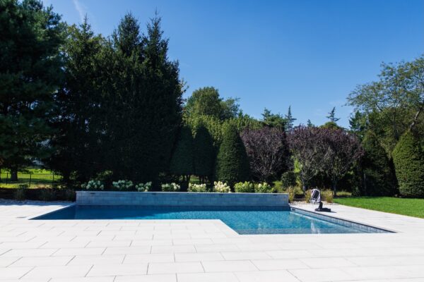 Scenic View Landscaping transformed a Colts Neck backyard into a modern outdoor oasis with Techo-Bloc pavers, Raffinato coping, triple waterfall spillways, outdoor kitchen, and custom lighting.