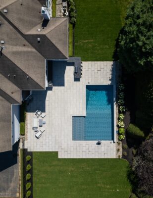 Scenic View Landscaping transformed a Colts Neck backyard into a modern outdoor oasis with Techo-Bloc pavers, Raffinato coping, triple waterfall spillways, outdoor kitchen, and custom lighting.