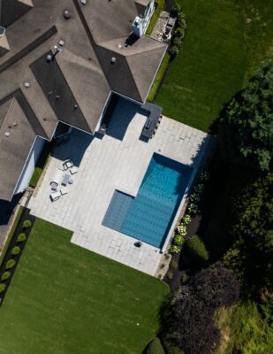 Scenic View Landscaping transformed a Colts Neck backyard into a modern outdoor oasis with Techo-Bloc pavers, Raffinato coping, triple waterfall spillways, outdoor kitchen, and custom lighting.