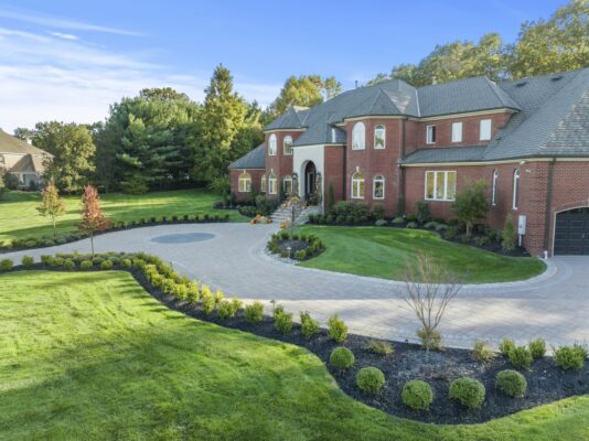 A complete front yard transformation in Colts Neck, NJ featuring a custom paver driveway, entrance steps, and professionally designed landscaping.