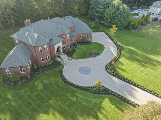 A complete front yard transformation in Colts Neck, NJ featuring a custom paver driveway, entrance steps, and professionally designed landscaping.