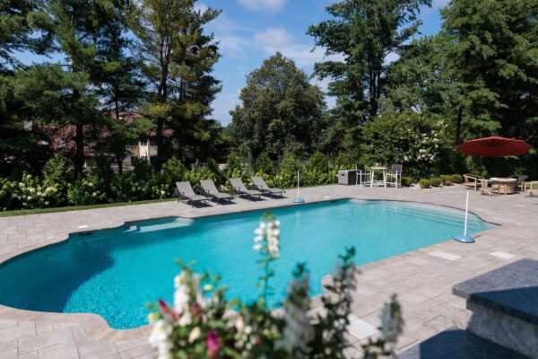 Multi-level patio design in Colts Neck, NJ featuring a pool patio, retaining wall with steps, and raised patio with built-in lighting.