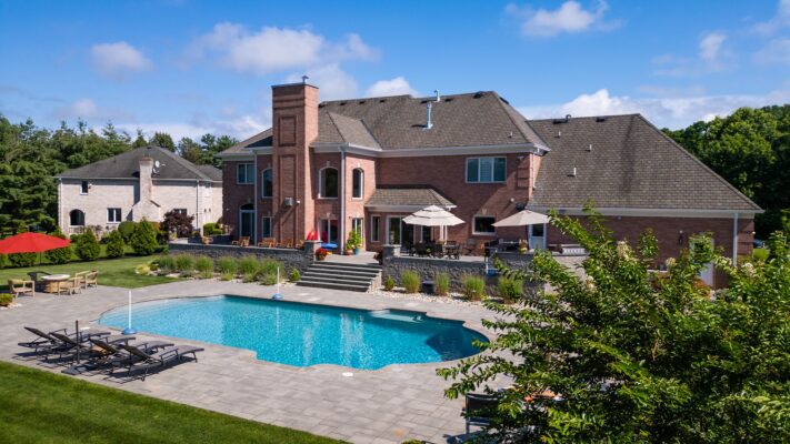 Multi-level patio design in Colts Neck, NJ featuring a pool patio, retaining wall with steps, and raised patio with built-in lighting.