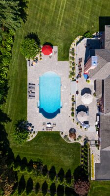 Multi-level patio design in Colts Neck, NJ featuring a pool patio, retaining wall with steps, and raised patio with built-in lighting.