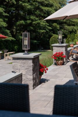 Multi-level patio design in Colts Neck, NJ featuring a pool patio, retaining wall with steps, and raised patio with built-in lighting.