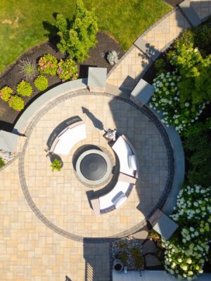 Complete outdoor transformation in Lincroft, NJ featuring a custom pool patio, fire pit patio with seating wall, stone steps, and a paver walkway connecting the backyard to the front.