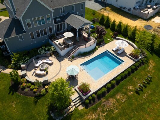 Complete outdoor transformation in Lincroft, NJ featuring a custom pool patio, fire pit patio with seating wall, stone steps, and a paver walkway connecting the backyard to the front.