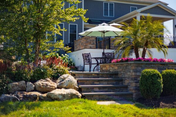 Complete outdoor transformation in Lincroft, NJ featuring a custom pool patio, fire pit patio with seating wall, stone steps, and a paver walkway connecting the backyard to the front.