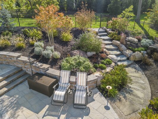 Two-level pool patio in Middletown, NJ featuring a stone retaining wall, natural stone steps, and a paver walkway connecting the backyard to the front yard.