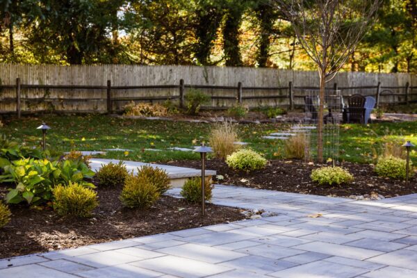 Outdoor living project in Rumson, NJ featuring a covered paver patio, outdoor kitchen, stone steps, natural stone walkway, and fire pit area.