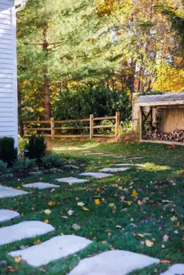 A covered paver patio with built-in outdoor kitchen, stone steps, natural stone walkway, and a dedicated fire pit area tied together with plantings and landscape lighting.