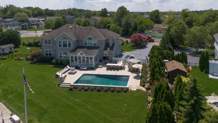 Outdoor living project in Rumson, NJ featuring a covered paver patio, outdoor kitchen, stone steps, natural stone walkway, and fire pit area.