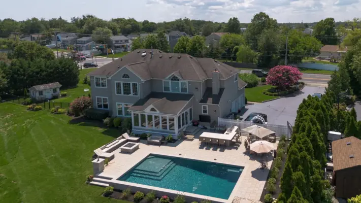 Outdoor living project in Rumson, NJ featuring a covered paver patio, outdoor kitchen, stone steps, natural stone walkway, and fire pit area.
