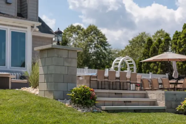 Outdoor living project in Rumson, NJ featuring a covered paver patio, outdoor kitchen, stone steps, natural stone walkway, and fire pit area.