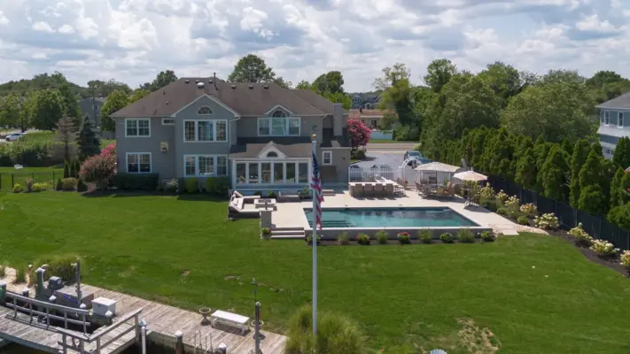 Outdoor living project in Rumson, NJ featuring a covered paver patio, outdoor kitchen, stone steps, natural stone walkway, and fire pit area.